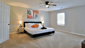 A bedroom with a bed, two bedside tables, a ceiling fan, and a window. - 5BR, 3BA Spacious N. Columbus Villa w/Hot Tub, BBQ, Play Area, 13 mi. to Benning (Columbus)