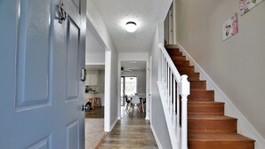 A hallway with a wooden staircase, a white door, and a ceiling fan. - 5BR, 3BA Spacious N. Columbus Villa w/Hot Tub, BBQ, Play Area, 13 mi. to Benning (Columbus)