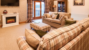 A cozy living room with a fireplace, a sofa set, a television, and a painting on the wall.