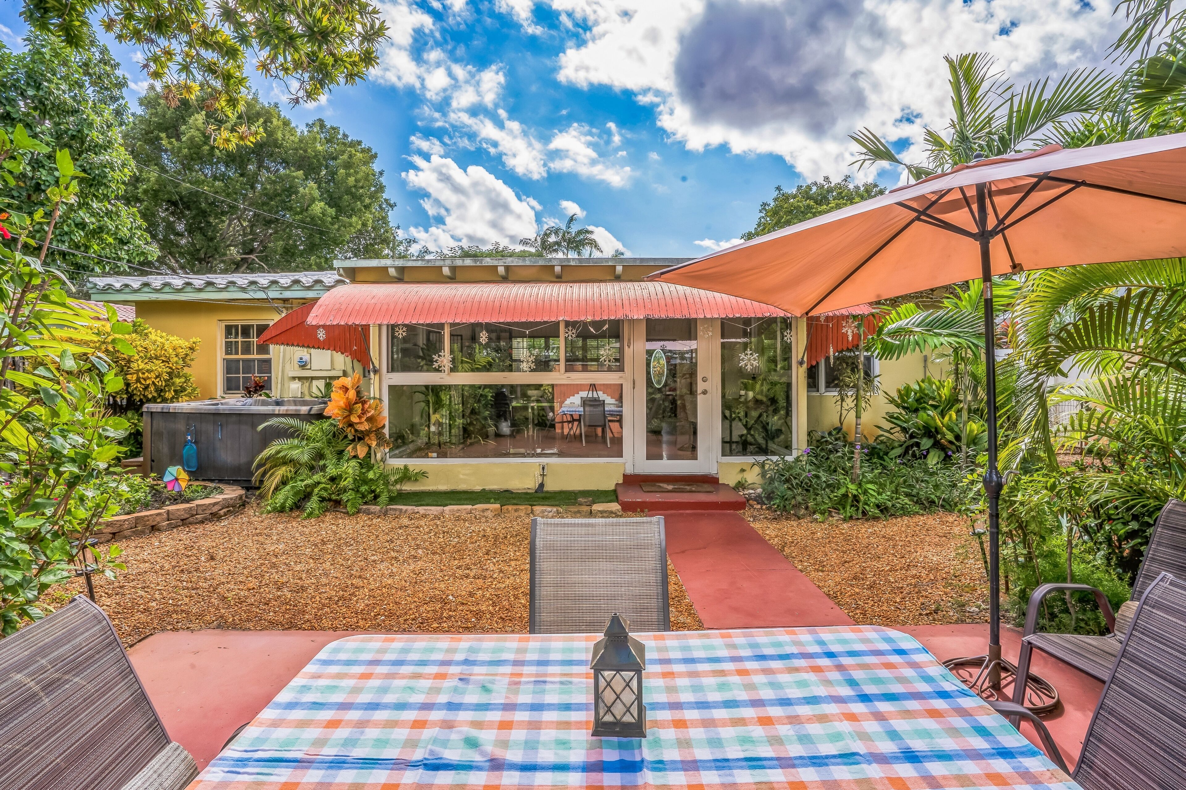 A patio with a checkered table, a lantern, and outdoor furniture.