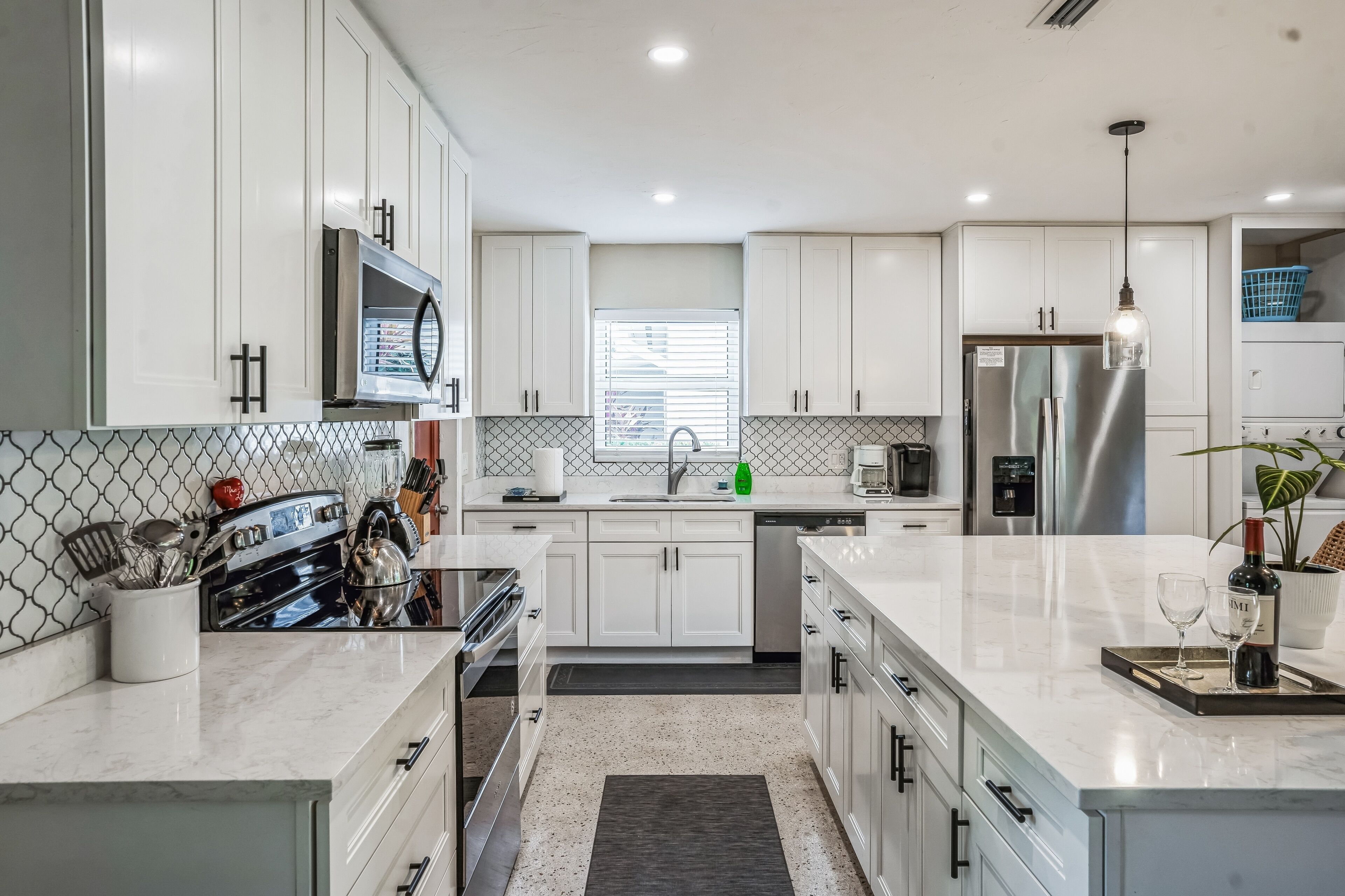 Una cocina moderna con armarios blancos, electrodomésticos de acero inoxidable y una isla central.
