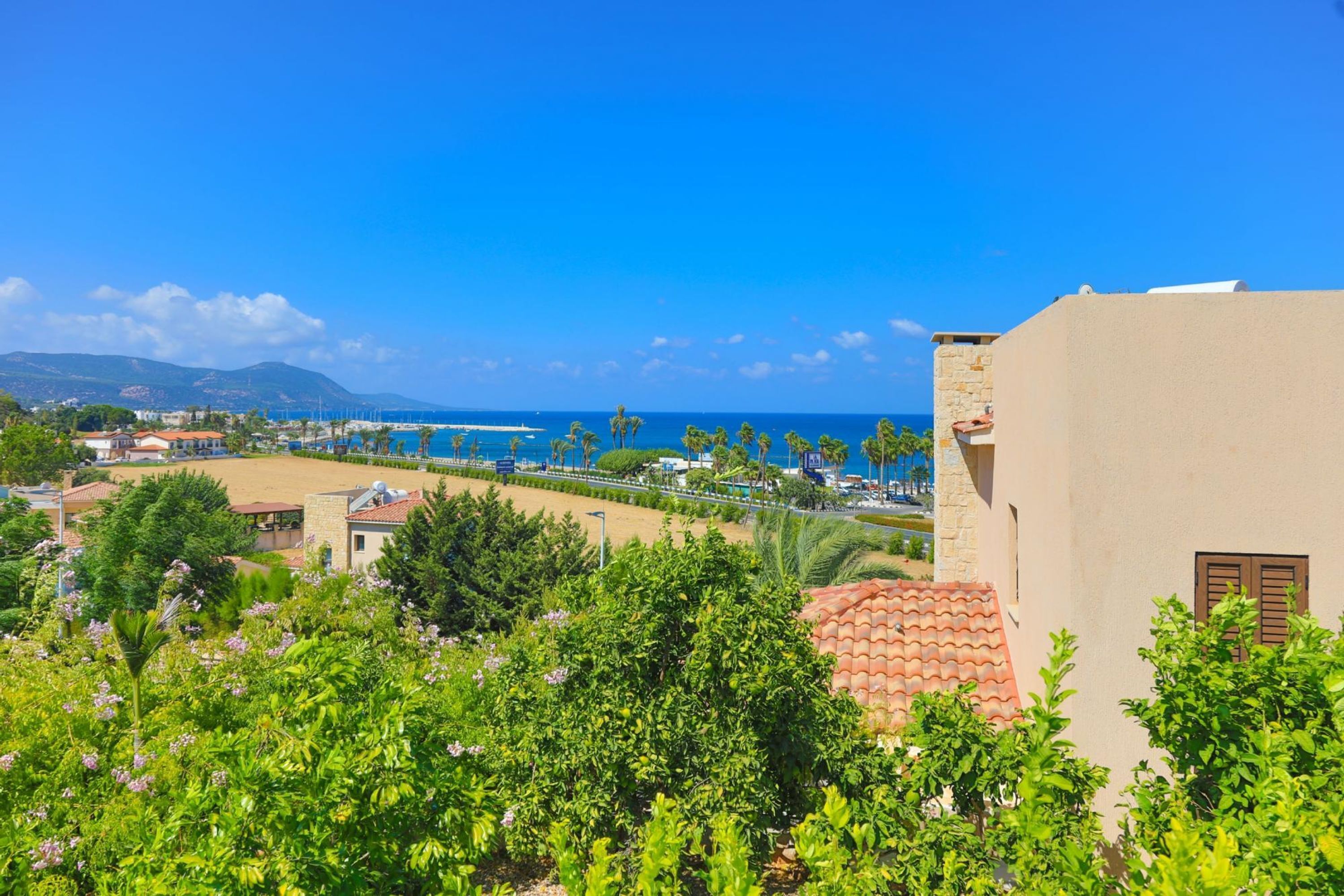 Una vista costiera con cielo sereno, spiaggia e un edificio con tetto in tegole rosse.
