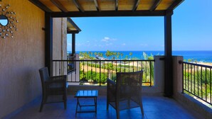 A balcony with wicker chairs and a small table, overlooking a beach with palm trees and the ocean. - Villa Arbanassi in Latchi (Polis)