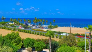 A coastal area with a beach, palm trees, and parked cars. - Villa Arbanassi in Latchi (Polis)