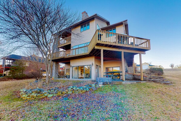 A two-story house with a balcony, a stone fireplace, and a covered porch.