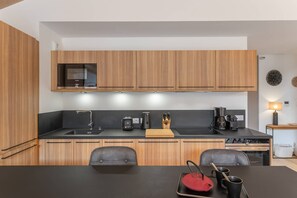 A modern kitchen with wooden cabinets, a black countertop, and a dining area with a table and chairs.