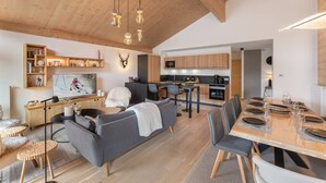Et moderne opholdsrum med sofa, spisebord, køkken og en opsat dekoration af et hjortehoved.