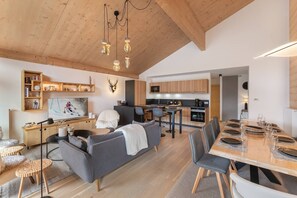 A modern living space with a sofa, dining table, kitchen, and a mounted deer head decoration.