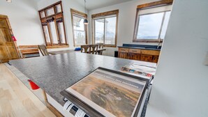 A spacious kitchen with a granite countertop, wooden cabinets, and large windows offering views of the outdoors. - Montana Skies, Livingston, MT! Skiing / Fishing / Yellowstone! (Livingston)
