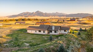 A single-story house with a sloped roof, surrounded by open fields and distant mountains. - Montana Skies, Livingston, MT! Skiing / Fishing / Yellowstone! (Livingston)