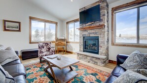 A living room with a stone fireplace, large windows, a sofa, and a coffee table. - Montana Skies, Livingston, MT! Skiing / Fishing / Yellowstone! (Livingston)