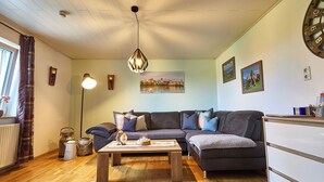 Un salon chaleureux avec un canapé gris foncé, une table basse en bois et une suspension décorative.
