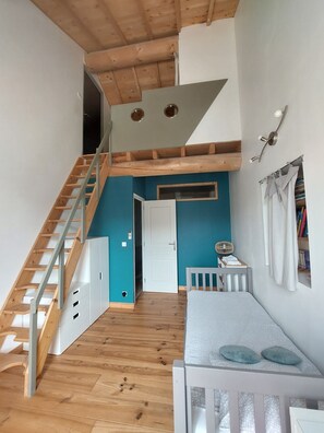 A loft-style bedroom with a wooden staircase, a small seating area, and a white door leading to another room. - Bastide d'Exception 18ᵉ - Heated Pool  in the heart of the Luberon (Robion)