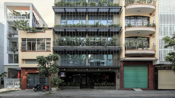 Un edificio de varios pisos con balcones, una verja verde y un escaparate.