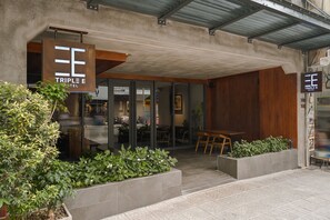 The exterior of the Triple E Hotel with a modern design, including a covered entrance, outdoor seating area, and well-maintained landscaping.
