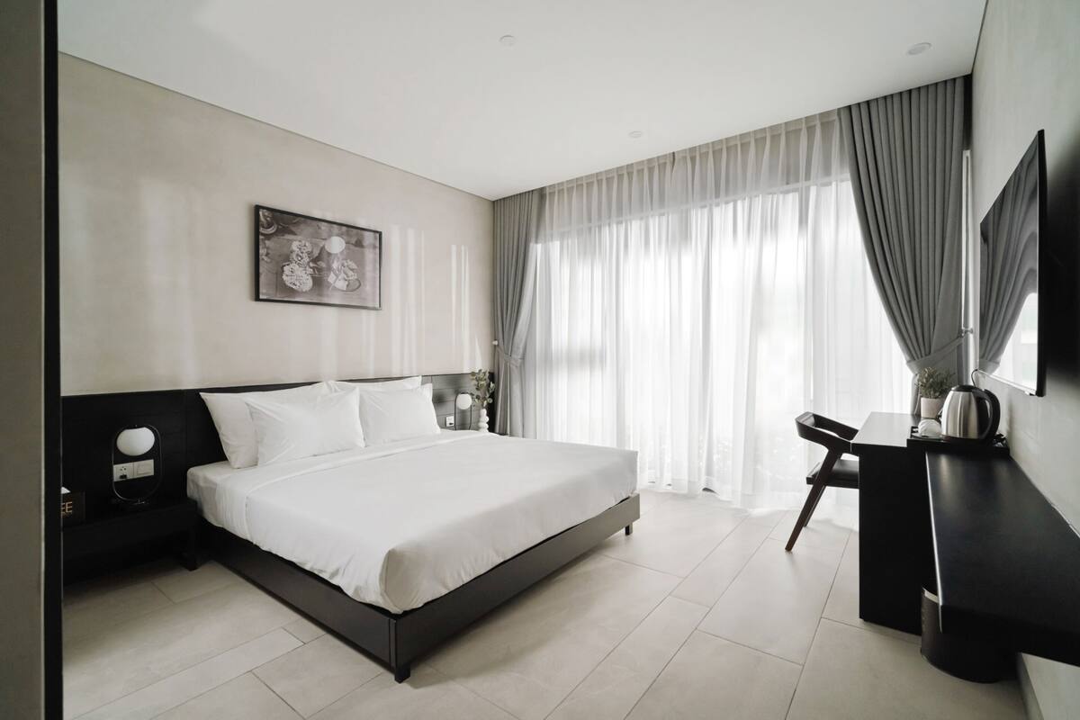 A modern hotel room with a large bed, a desk, and a television.