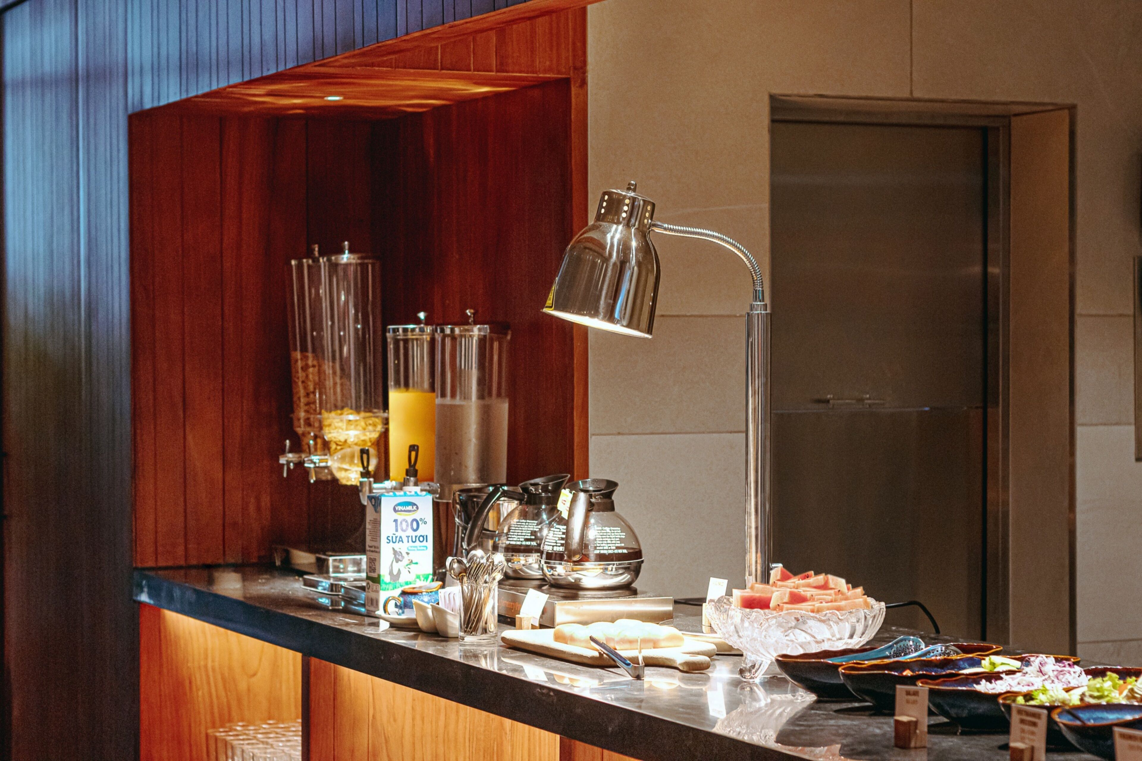 A breakfast bar with a coffee machine, tea pots, and a variety of food items.