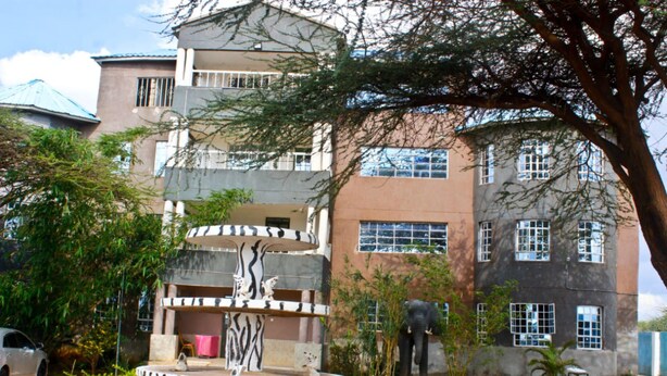 A multi-story building with a central courtyard featuring a fountain and sculptures. - Lapset Hotel (Isiolo)