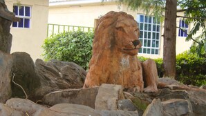 A lion statue surrounded by rocks and greenery. - Lapset Hotel (Isiolo)
