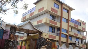 A multi-story building with balconies, a stone entrance, and a sign for a bank. - Lapset Hotel (Isiolo)