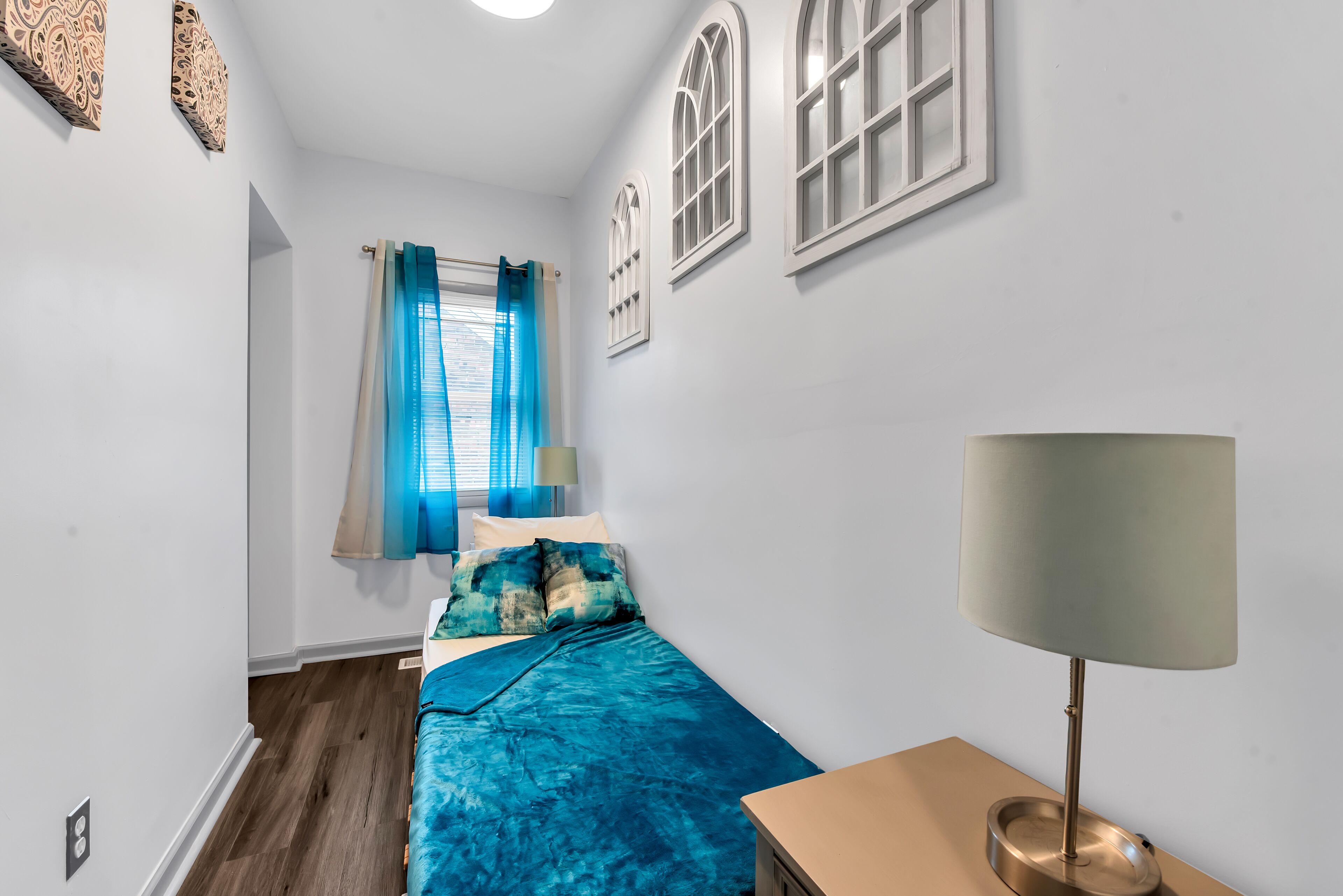 Un dormitorio con cama, lámpara y ventana con cortinas.
