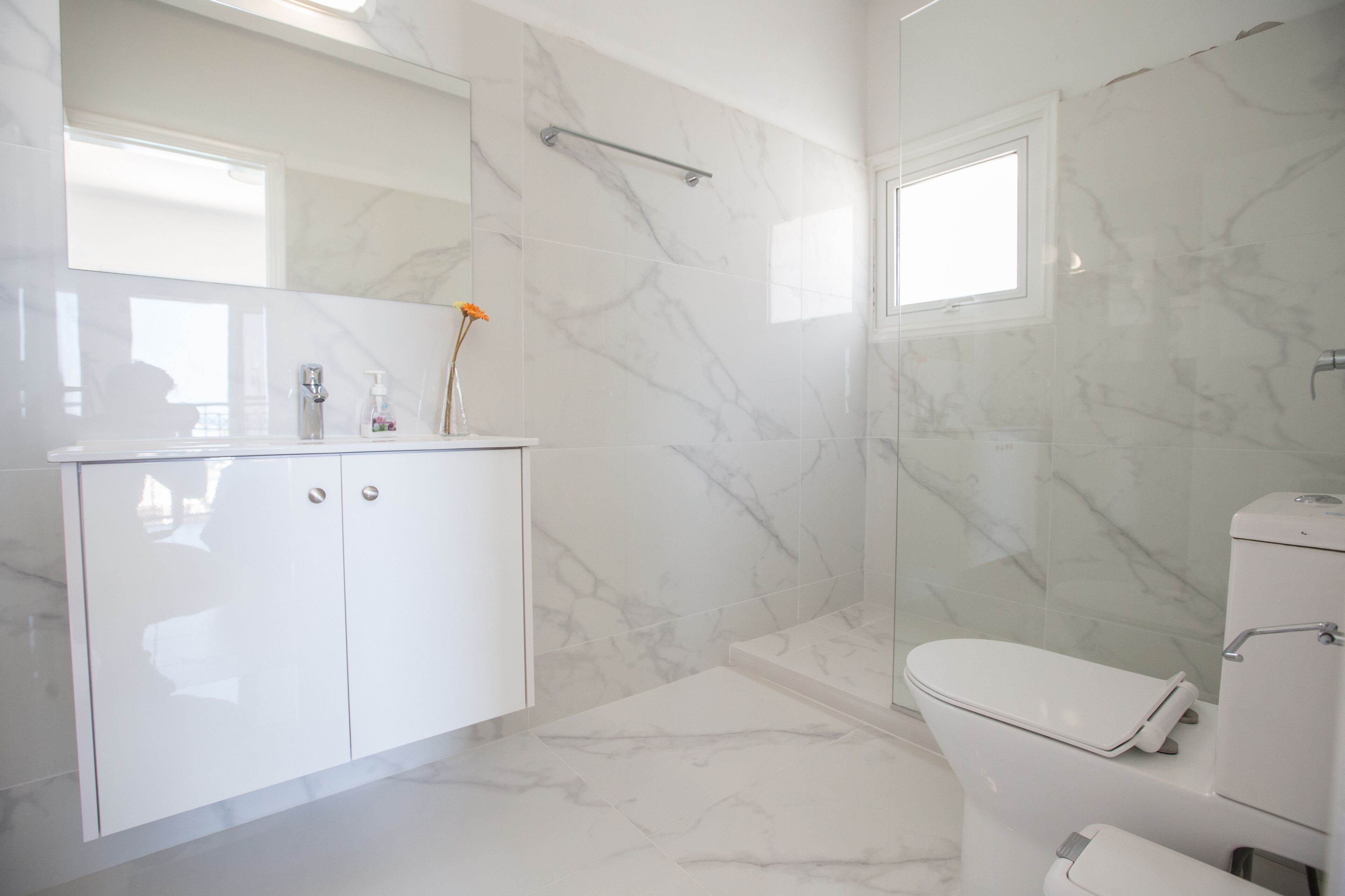 Un bagno moderno con un lavabo in marmo bianco, un water e una zona doccia.
