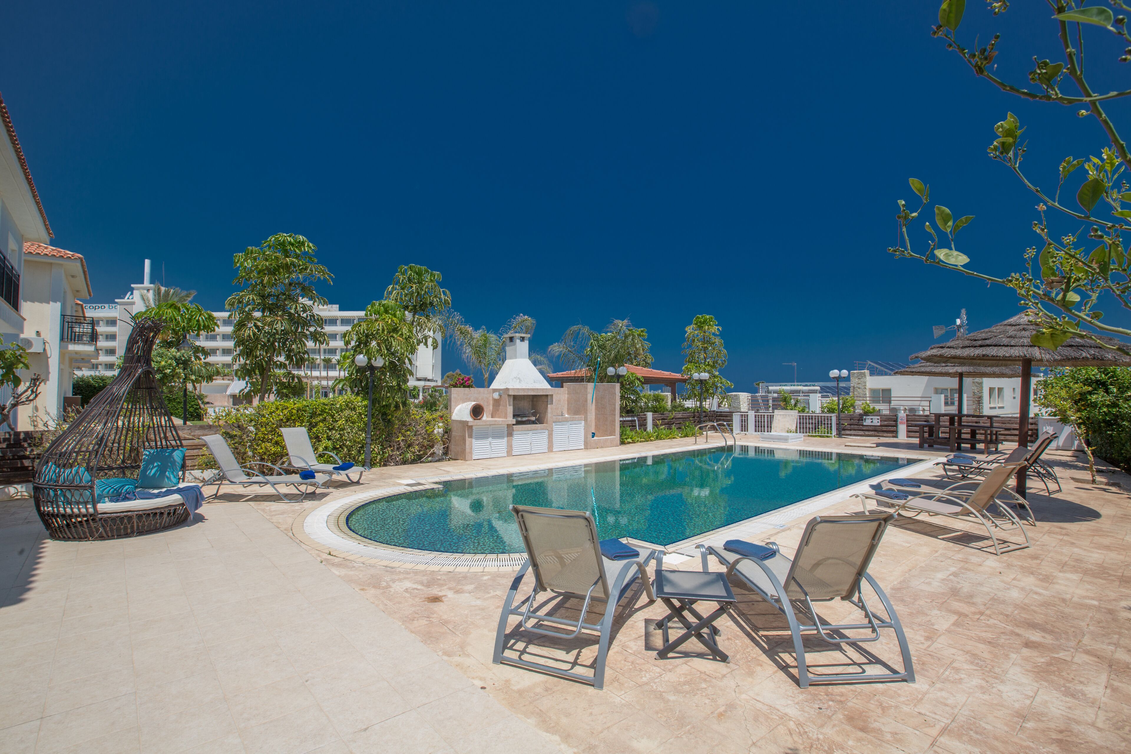 A pool area with lounge chairs and a cabana.