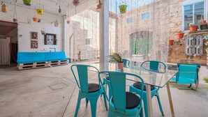 A room with a glass table, teal chairs, a blue bench, and hanging baskets. - Holiday Home "Townhouse Can Miquel" with Pool, Garden and Wi-Fi (Sa Pobla)