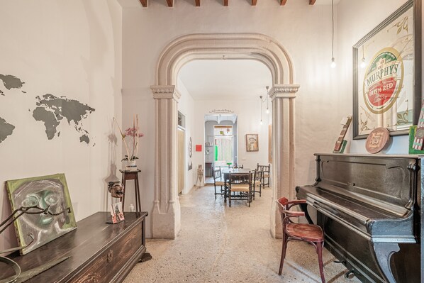 A room with a piano, a world map on the wall, and a dining area in the background.