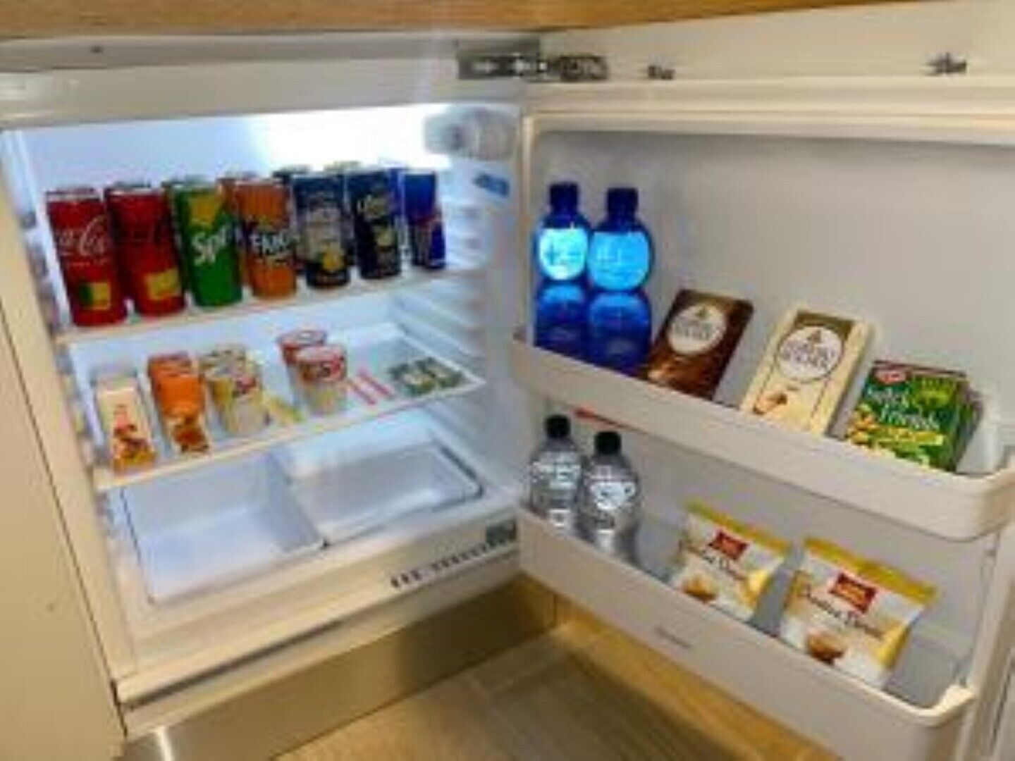 A refrigerator stocked with various beverages and snacks.