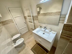 A modern bathroom with a white sink, mirror, and toilet. - Channel Suite - 3 (Sinalunga)