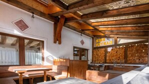 Un interior rústico de madera con bancos y mesas, una pared de madera con un letrero y una ventana con cortinas.