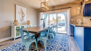 A dining area with a wooden table, blue chairs, and a patterned rug. - Sandal Escape: 6BR Canal Front Oasis w/ Heated Pool, Dog-Friendly, Dockage & Fast Atlantic Access (Marathon)