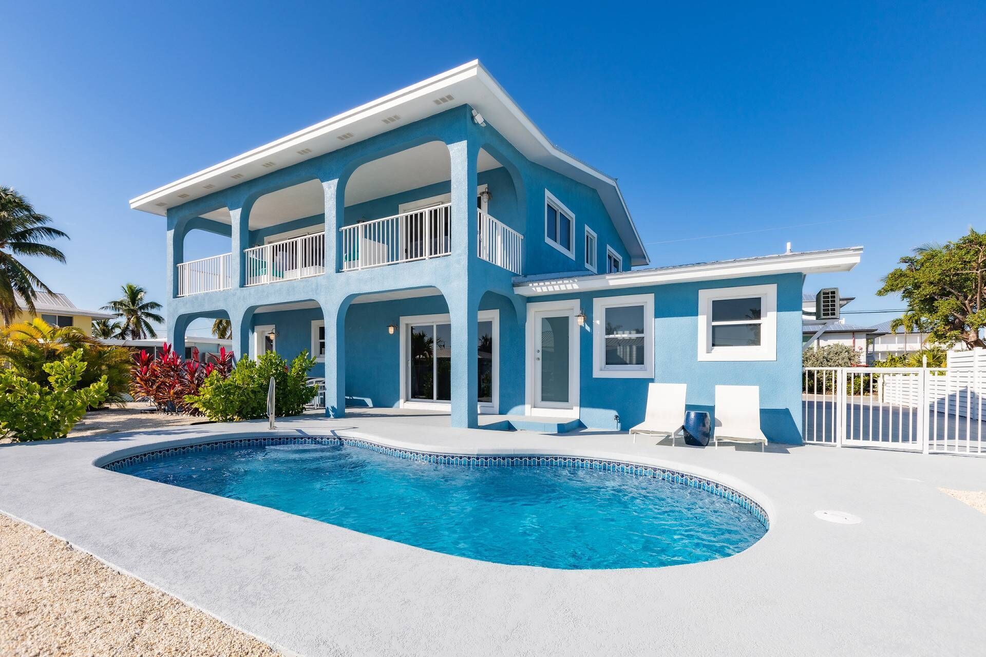 A two-story house with a swimming pool, a balcony, and a fenced yard.