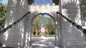 A stone archway with chains, leading to a building with a red roof. - Resort Home 3.5 miles to Disney with home theater (Kissimmee)