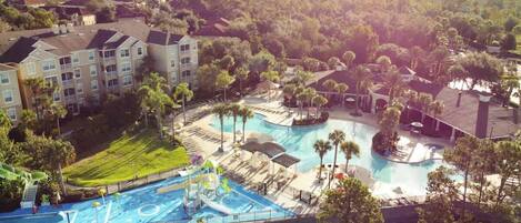 Un resort con varias piscinas, un tobogán de agua y un amplio césped bien cuidado.