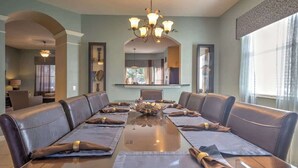 A conference room with a long table, leather couches, and a chandelier. - Resort Home 3.5 miles to Disney with home theater (Kissimmee)