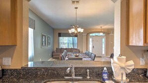 A kitchen with a double sink, a chandelier, and a dining area with a sofa and table. - Resort Home 3.5 miles to Disney with home theater (Kissimmee)