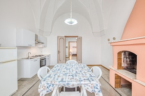 A compact kitchen with a dining table, chairs, a built-in oven, and a fireplace.