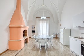 A kitchen with a central island, white cabinetry, and a chimney.