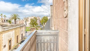 Vista desde un balcón sobre un paisaje urbano con edificios, palmeras y cielo despejado.