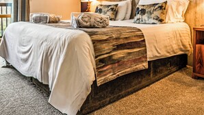 A hotel room with a large bed, a wooden headboard, a nightstand, a lamp, and a window with a view. - 2 bedroom accommodation in Balmaha (Balmaha)