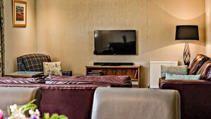 A modern living room with a flat-screen TV, leather sofas, a coffee table, and a lamp. - 2 bedroom accommodation in Balmaha (Balmaha)