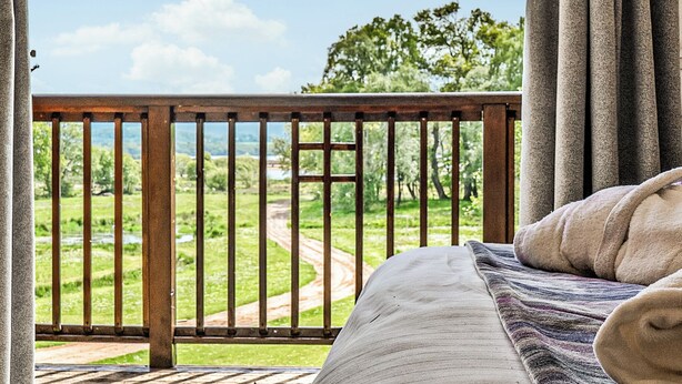 A bedroom with a view of a green landscape through a balcony railing. - 2 bedroom accommodation in Balmaha (Balmaha)