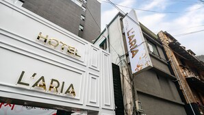 Un letrero de hotel con el nombre 'HOTEL L'ARIA' en letras doradas sobre un fondo blanco.