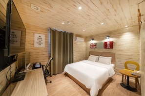 A wooden-paneled room with a bed, desk, chair, and a television. - HOTEL LARIA (Suwon)