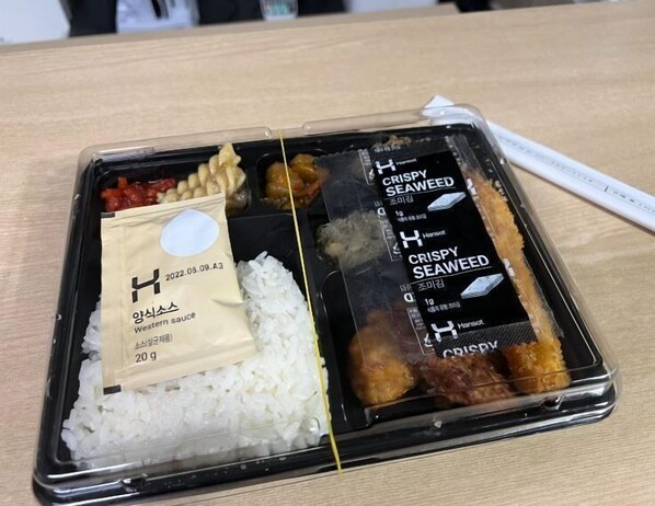 A bento box with rice, crispy seaweed, and a packet of western sauce.