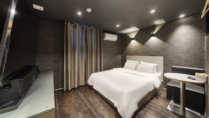 Una habitación de hotel moderna con una cama grande, una mesita redonda y un escritorio con una computadora.