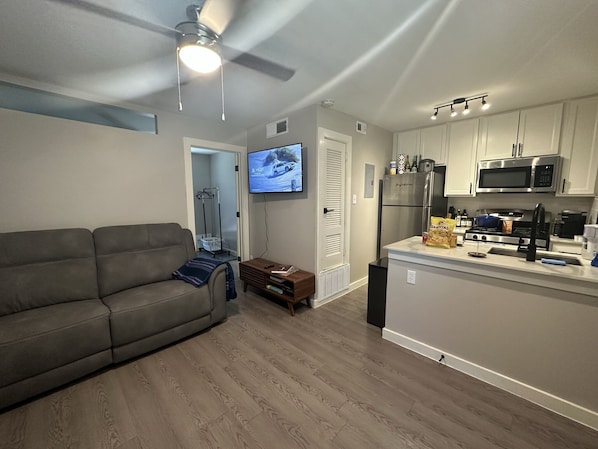 Relax in this cozy living space with a sofa, flat-screen TV, and fully equipped kitchen area.