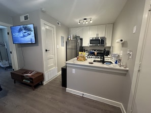 Compact kitchen with modern design, featuring a microwave, refrigerator, and island with sink and countertop.